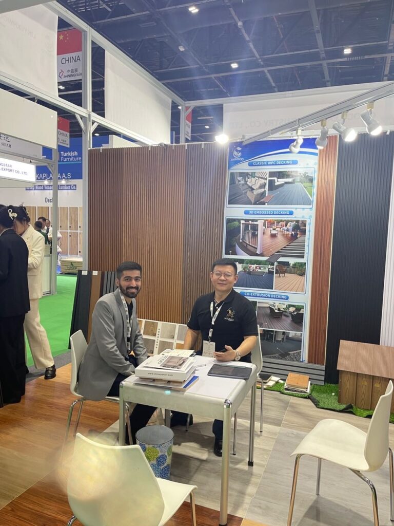Two men meeting at construction materials trade show booth with wood panel displays