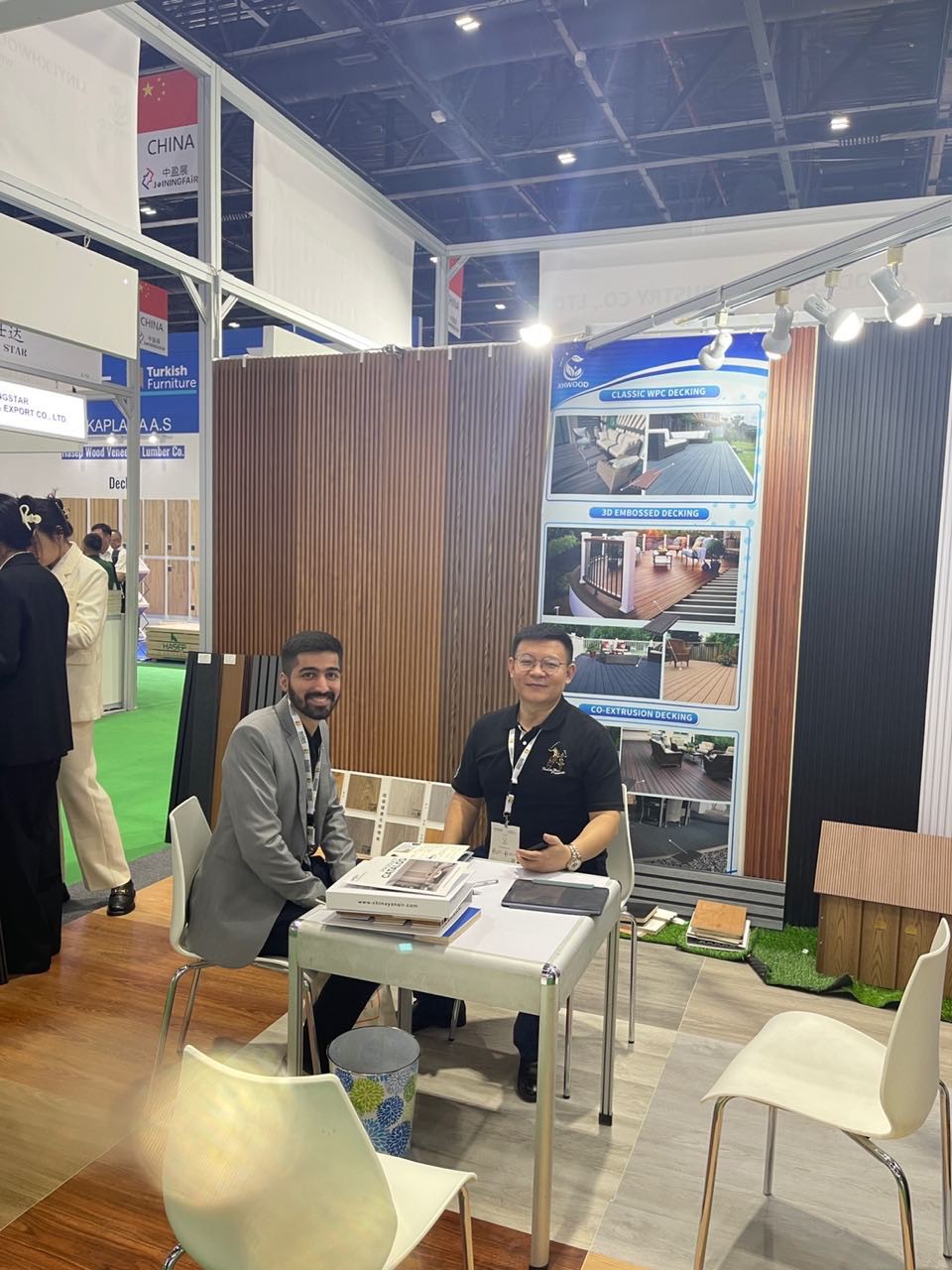 Two men meeting at construction materials trade show booth with wood panel displays