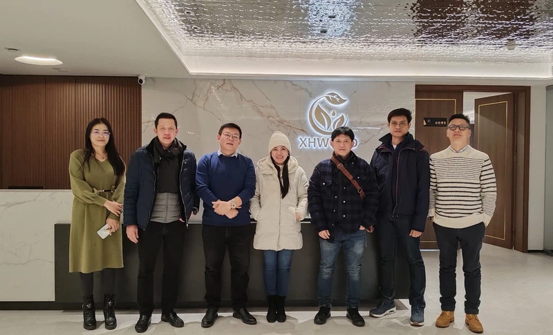 Seven-person business team posing in modern office lobby with company logo