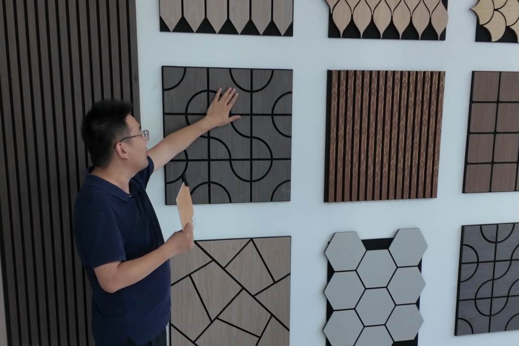 Designer evaluating decorative acoustic wall panels with geometric patterns in showroom