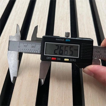 Digital caliper measuring 26.65 mm groove width on slatted wall panel