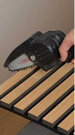 Handheld mini chainsaw held above wooden slats for precise pruning and woodworking