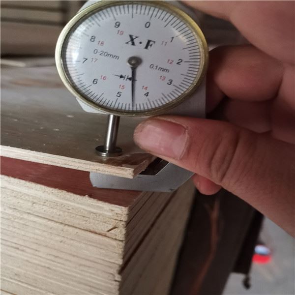 Dial thickness gauge measuring plywood thickness in woodworking workshop