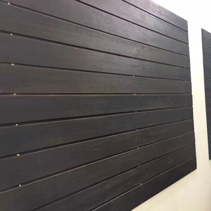 Modern dark wood slat wall paneling with horizontal panels on a light wall