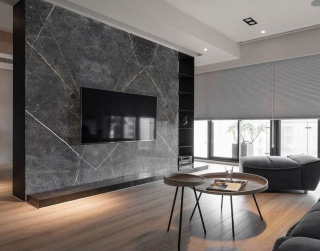 Modern minimalist living room with dark marble TV wall, gray sofa, and natural light
