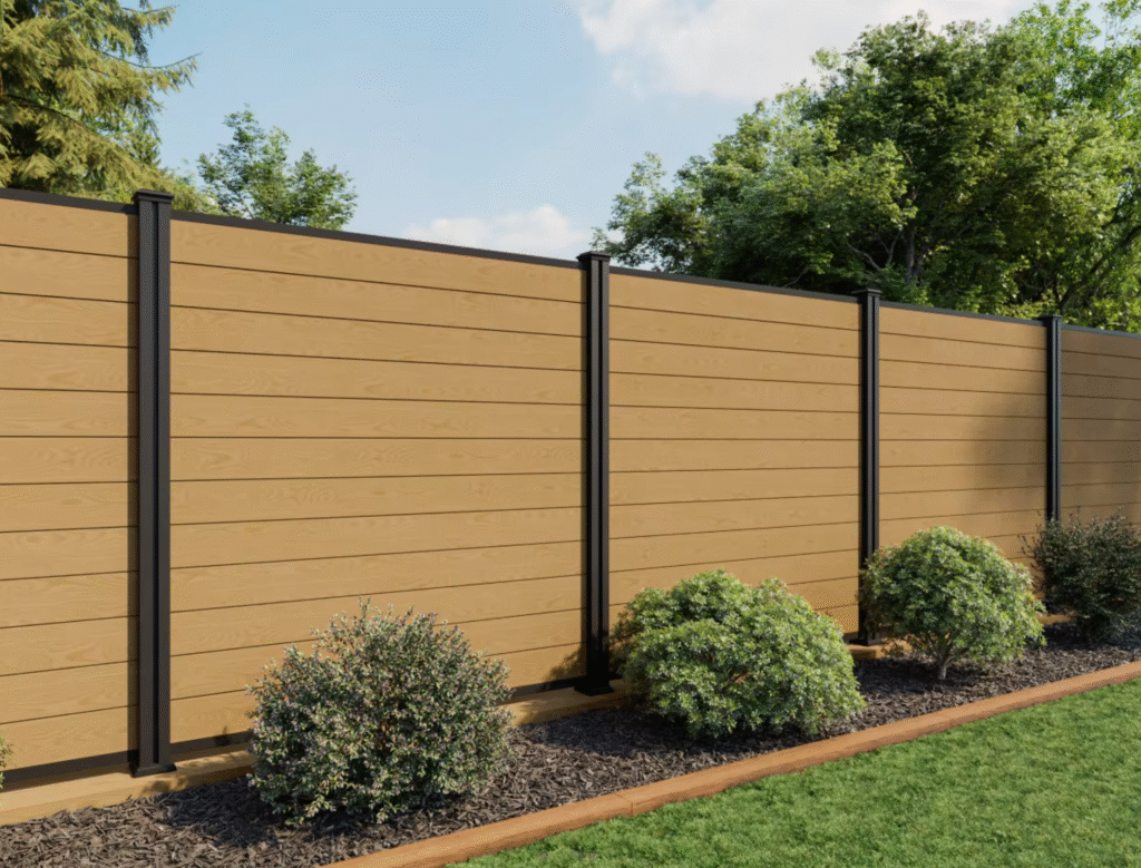 Modern wooden fence with horizontal slats, shrubs, mulch bed, and manicured green lawn.