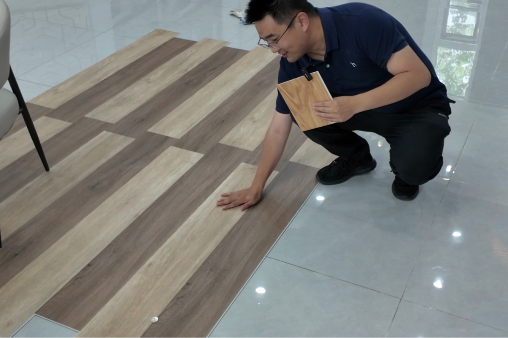 Man inspecting SPC vinyl flooring planks on tiled floor indoors