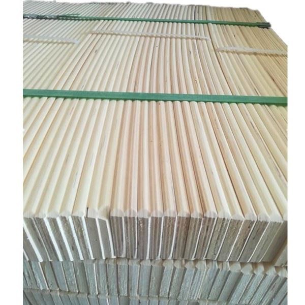 Neatly stacked wooden dowels bundled with green strap for storage and transport